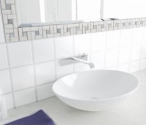helle Bordüre umrahmt den Badezimmerspiegel zwischen weißen Wandfliesen